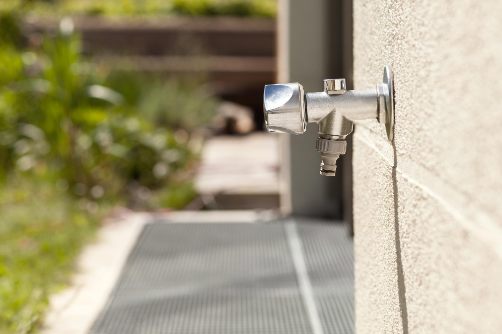 A frost-free spigot emerges from a wall.