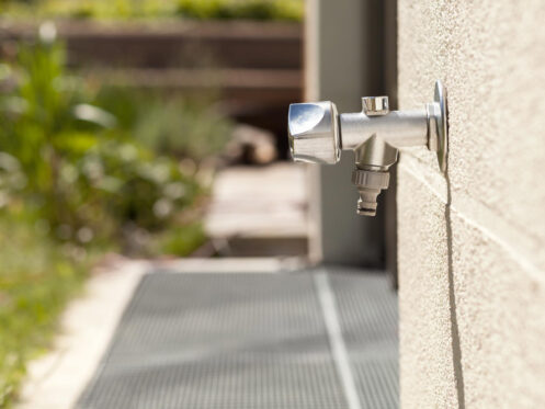 A frost-free spigot emerges from a wall.